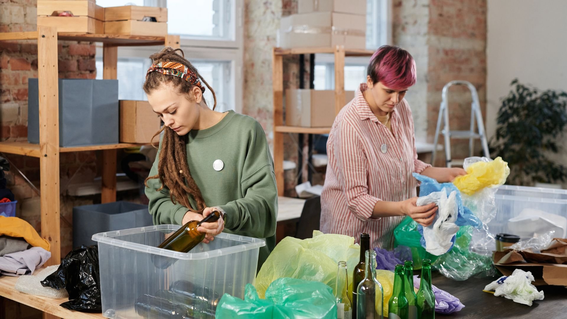 Two people sorting recyclable materials in a warehouse with plastic bags